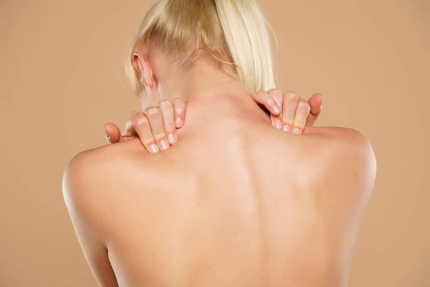 Donna con dolore alla spalla su sfondo beige - Foto, immagini