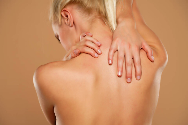 Vrouw met nekpijn op een beige achtergrond - Foto, afbeelding