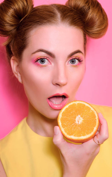 Portrait of stylish cute young blonde woman with oranges on pink background - Фото, зображення