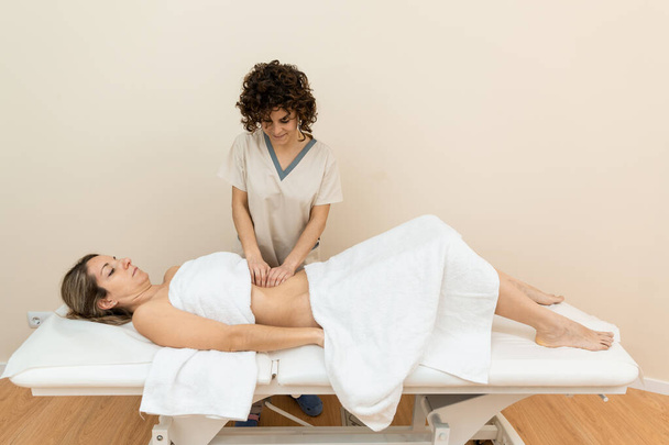 A therapist giving abdominal massage in female patient - Fotó, kép