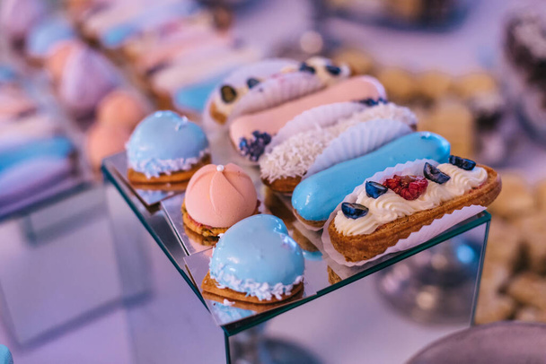 candy bar for the holiday, macaroons on the festive table, delicious eclairs fruit decoration - Photo, Image
