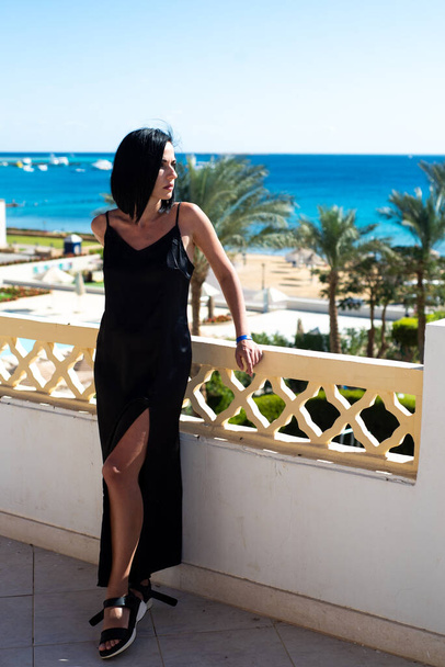 beautiful young woman in a black dress on the beach - Fotó, kép