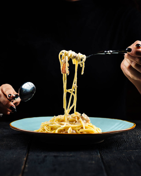 Comer espaguetis carbonara con tenedor y cuchara - Foto, imagen