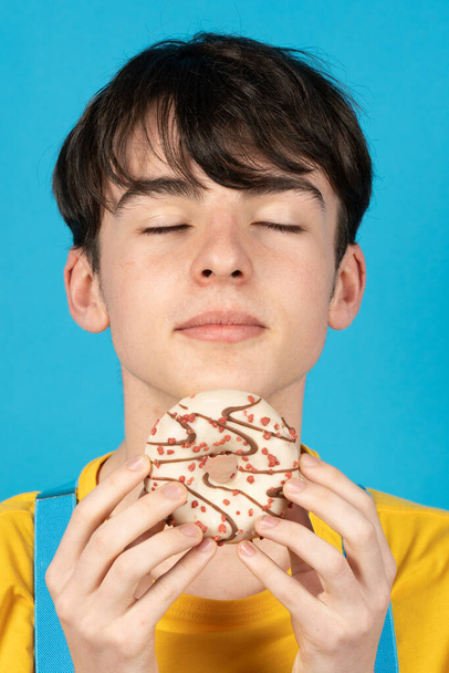 Teenager boy smelling sweet bun and resisting temptation. - Photo, Image