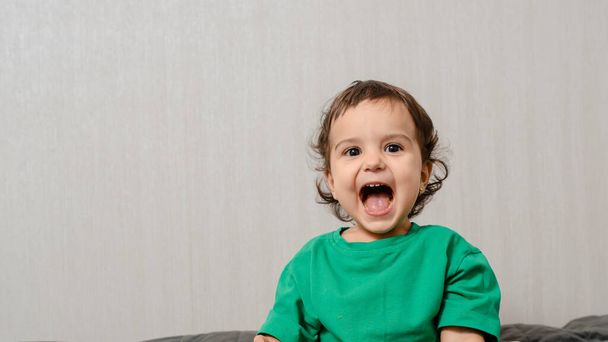 Menina criança em t-shirt verde um riso e sorriso no fundo cinza - Foto, Imagem