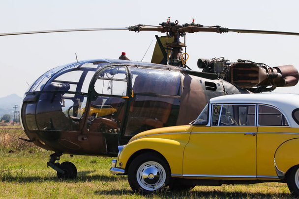 Lekki śmigłowiec wojskowy z żółtym klasycznym samochodem - Zdjęcie, obraz