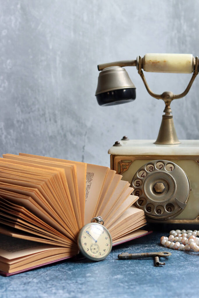 Bodegón de estilo retro con un libro abierto en un escritorio. Foto de cerca de objetos antiguos.  - Foto, Imagen
