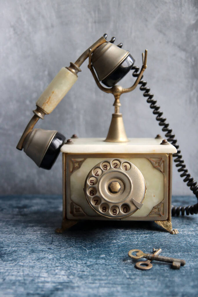 Ouderwetse roterende telefoon op een tafel. Vintage telefoon close-up foto. Grijze textuur achtergrond met kopieerruimte. - Foto, afbeelding