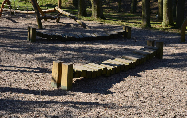 runder Schaukelstuhl, Hängematte aus Hanfseilen mit Stützen zwischen den Säulen im Garten auf dem Spielplatz, umgeben von einem niedrigen Zaun und einem Balken aus einem Schiffsseil, der über dem Boden schwebt - Foto, Bild