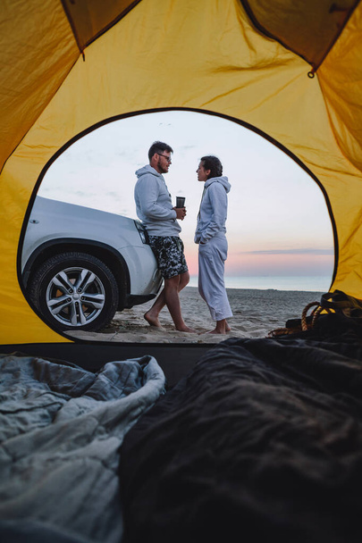 пара встречает восход солнца на морском пляже. вид через палатку для палаток. летний отдых - Фото, изображение
