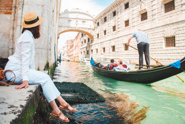 Frau sitzt am Stadtkai in Venedig Italien genießen den Blick auf Kanäle mit Gondeln Kopierraum - Foto, Bild