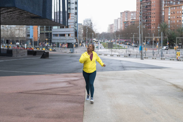 Afrykańska seniorka biegająca po mieście - Starsza Sportowa koncepcja stylu życia - Zdjęcie, obraz