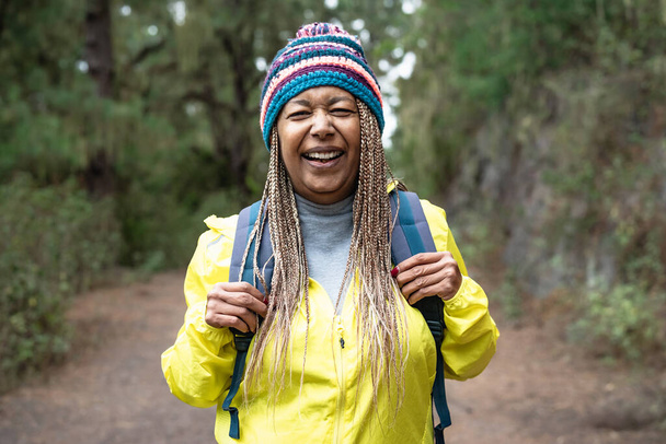 Glückliche Afro-Seniorin bei einem Waldspaziergang - Konzept für Abenteuer- und Reisemenschen - Foto, Bild