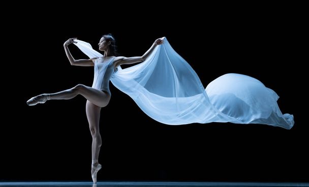 Graceful classic ballerina dancing with weightless fabric isolated on black studio background in neon. Theater, art, beauty, grace, action and motion concept. - Fotó, kép