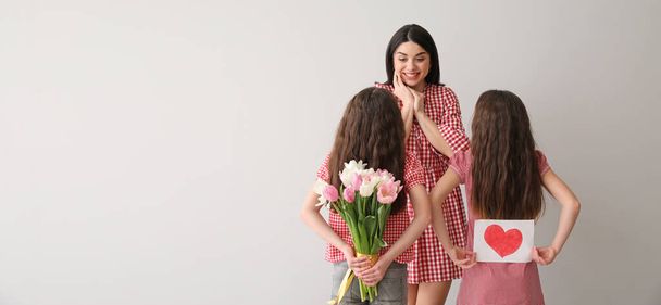 Kleine Mädchen grüßen ihre Mutter auf hellem Hintergrund mit Platz für Text. Muttertagsfeier - Foto, Bild