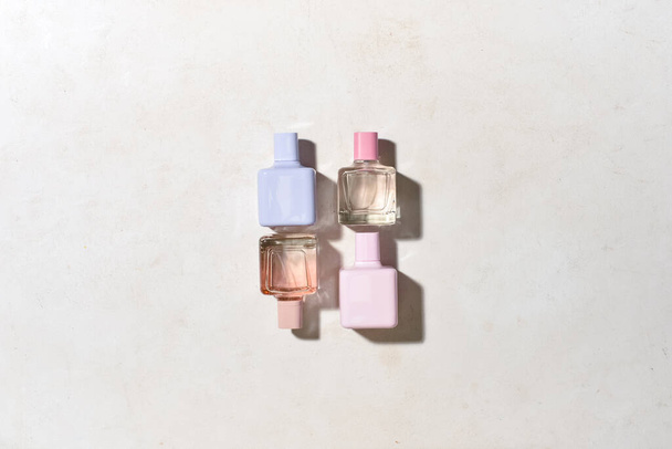 Bottles of different perfumes on light background, top view - Photo, image