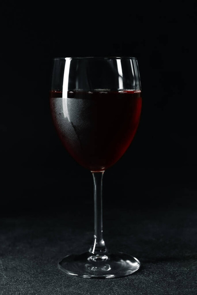 Glass of tasty red wine on dark background - 写真・画像