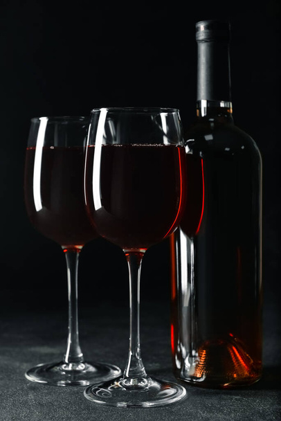 Gläser und Flasche schmackhaften Rotweins auf dunklem Hintergrund - Foto, Bild