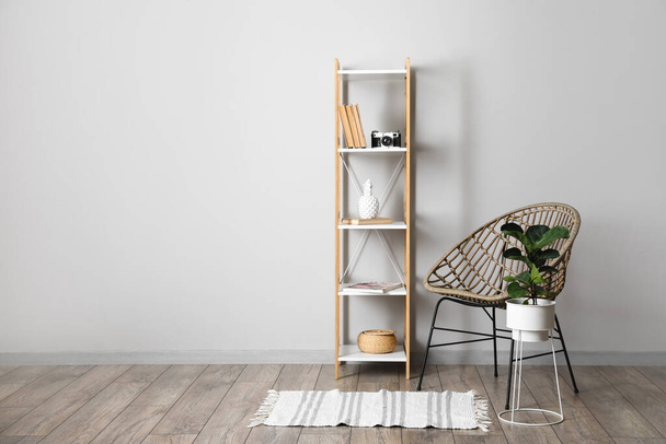 Shelving unit with chair and houseplant near light wall - Foto, Bild