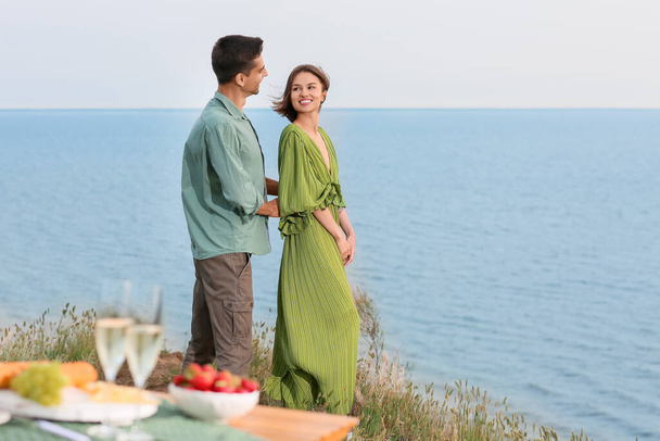 Happy young couple having romantic picnic near sea - Photo, Image