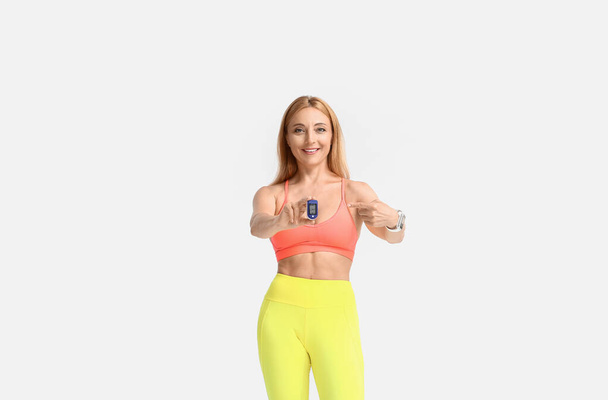 Vrouwelijke loper met pulsoximeter op lichte achtergrond - Foto, afbeelding
