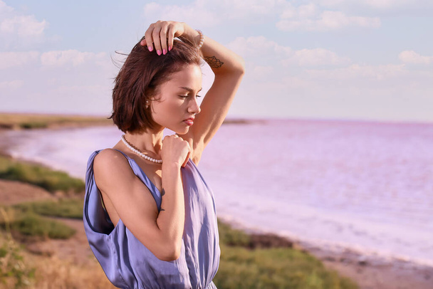 Stylische junge Frau posiert an einem Sommertag in der Nähe des rosa Sees - Foto, Bild