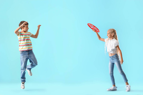 Lustige kleine Kinder spielen Frisbee auf farbigem Hintergrund - Foto, Bild