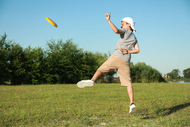 Cute little boy playing frisbee outdoors - Foto, afbeelding