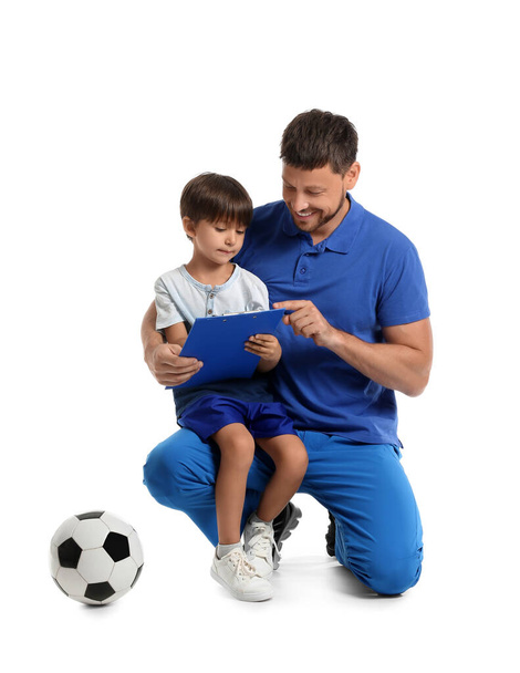 Мужской тренер с маленьким мальчиком и футбольный мяч на белом фоне - Фото, изображение