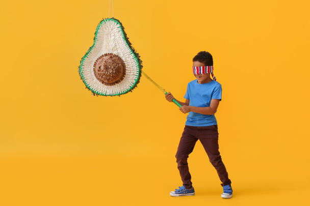 Kleiner Junge bricht mexikanische Pinata auf farbigem Hintergrund - Foto, Bild