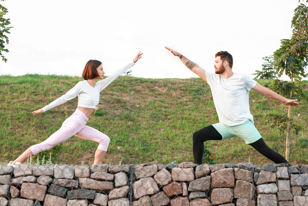 Sporty young couple doing yoga in park - Photo, Image