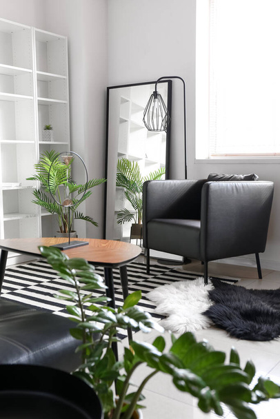 Удобное кресло, зеркало и напольная лампа в стильном интерьере гостиной - Фото, изображение