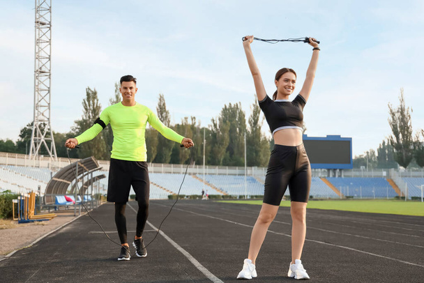 Sporty young couple with skipping ropes training in the stadium - Φωτογραφία, εικόνα