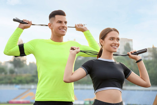 Sporty young couple with skipping ropes training in the stadium - Photo, Image