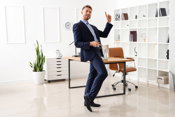 Красивый молодой бизнесмен танцует в офисе - Фото, изображение