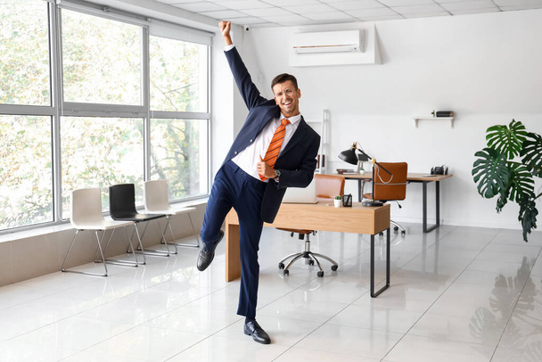 Танцующий молодой бизнесмен в офисе - Фото, изображение