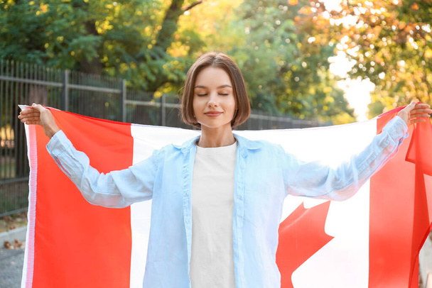 Beautiful young woman with flag of Canada outdoors - Foto, Imagen
