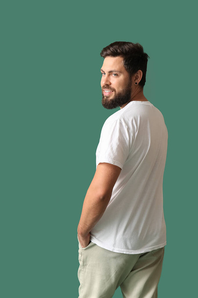 Jóképű férfi fehér pólóban, zöld háttérrel - Fotó, kép