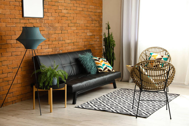 Интерьер стильной гостиной со стоячей лампой, стульями и черным диваном - Фото, изображение