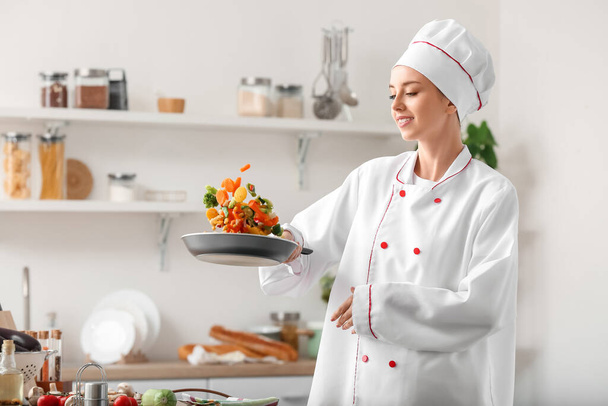 Female chef frying vegetables in kitchen - Zdjęcie, obraz