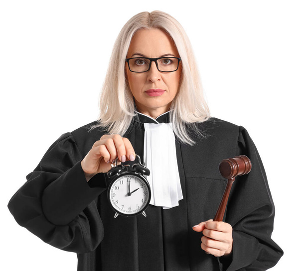 Ώριμη γυναίκα δικαστής με ρόμπα με σφυρί και ξυπνητήρι σε λευκό φόντο - Φωτογραφία, εικόνα