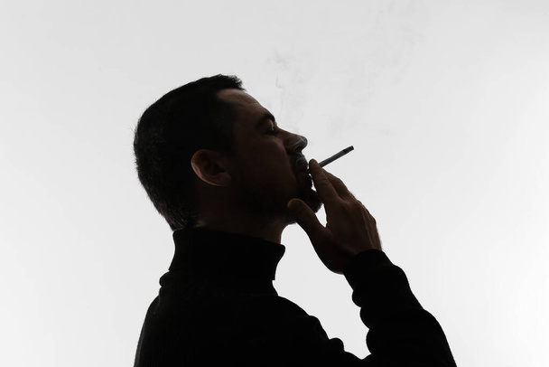 Silhouette of smoking man on light background - Foto, Bild