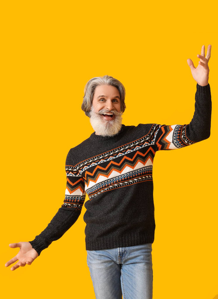Beau vieux homme heureux en pull tricoté sur fond jaune - Photo, image