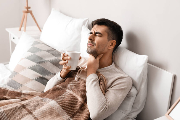 Хіба молодий чоловік з болем в горлі п'є гарячий чай вдома
 - Фото, зображення