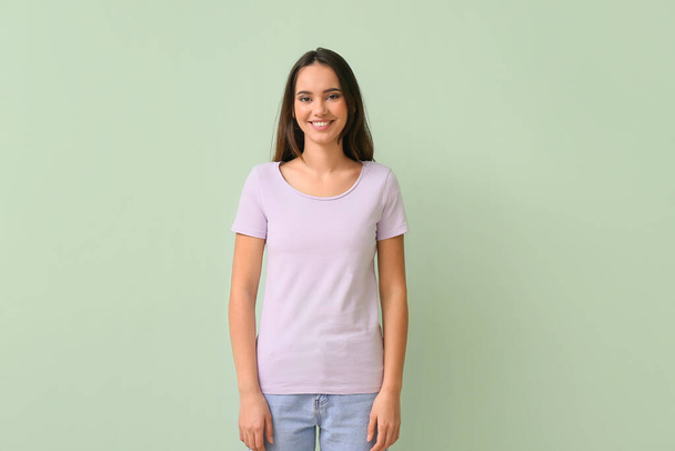 Pretty young woman in stylish t-shirt on green background - Foto, afbeelding