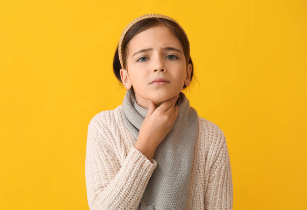 Sad little girl suffering from sore throat on yellow background - Photo, Image
