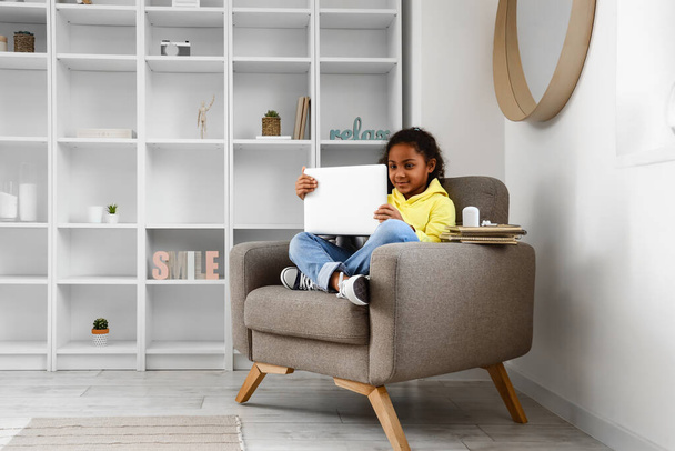 Little African-American girl studying with online tutor in armchair at home - Foto, Imagen