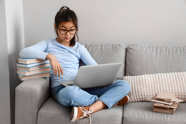 Gözlüklü küçük Asyalı kız evde online öğretmenle edebiyat okuyor. - Fotoğraf, Görsel