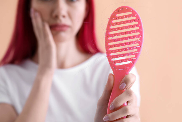 Красива молода жінка з проблемою випадіння волосся, використовуючи пензлик на кольоровому фоні, крупним планом
 - Фото, зображення
