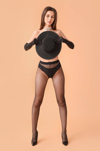 Sexy young woman in black tights on color background - Foto, afbeelding